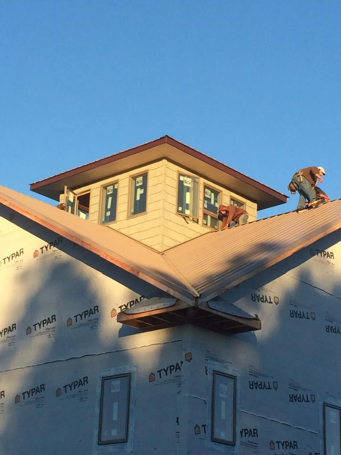 Roofers working around a rooftop cupola on a new metal roof at sunset — Roof Waterproofing in Lehigh Acres by Roofing Brothers